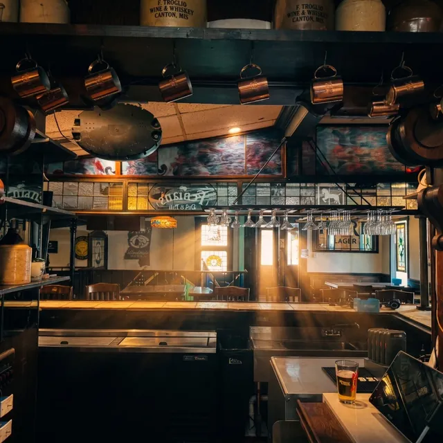 Behind the bar: whiskey crocks up top, copper mugs on hooks
