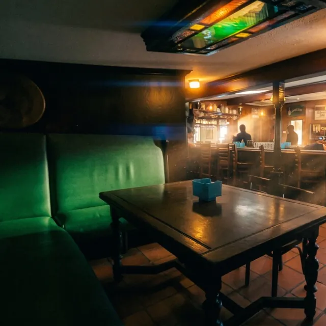 A green leather booth against the wall, facing the taps